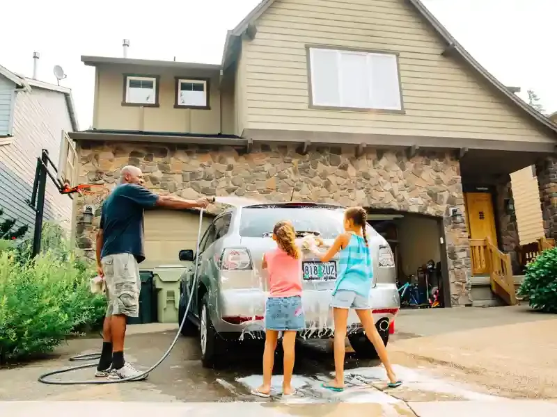 Family washing a car in the driveway.